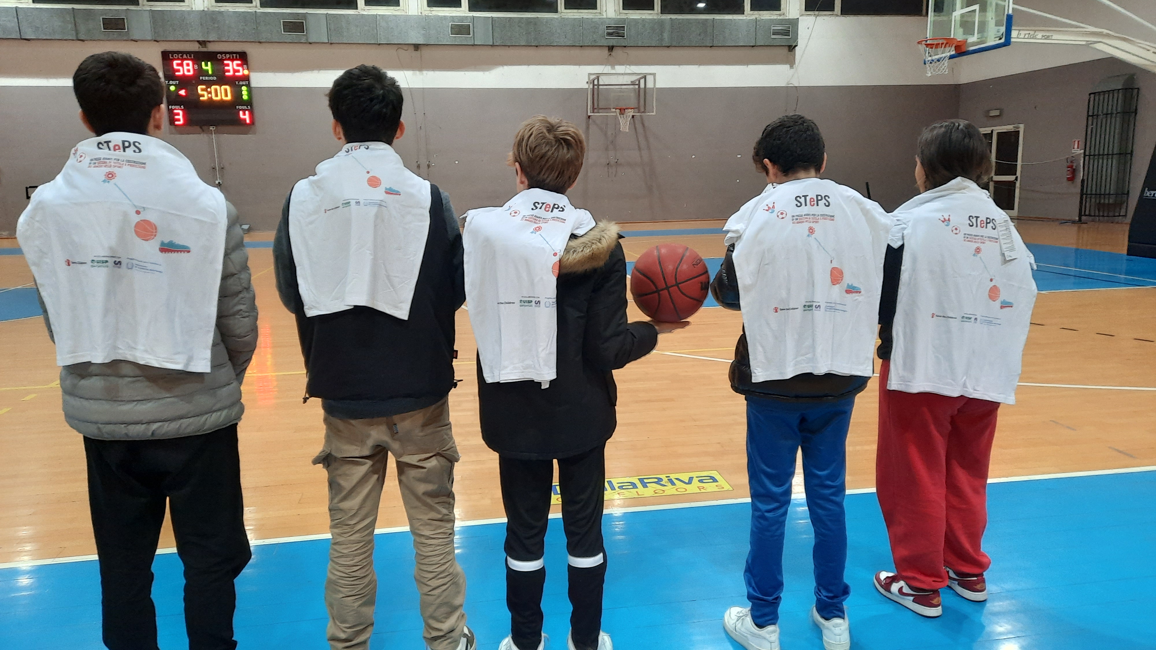 Ragazzə in un campo da basket con maglietta del progetto STEPS sulle spalle.